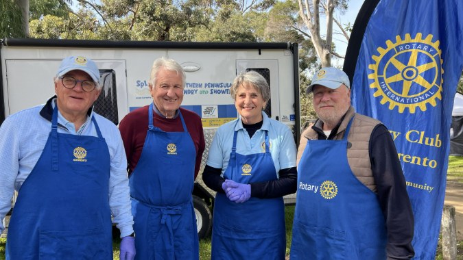 Rotary Club volunteers in aprons at a fundraising event for SPCS